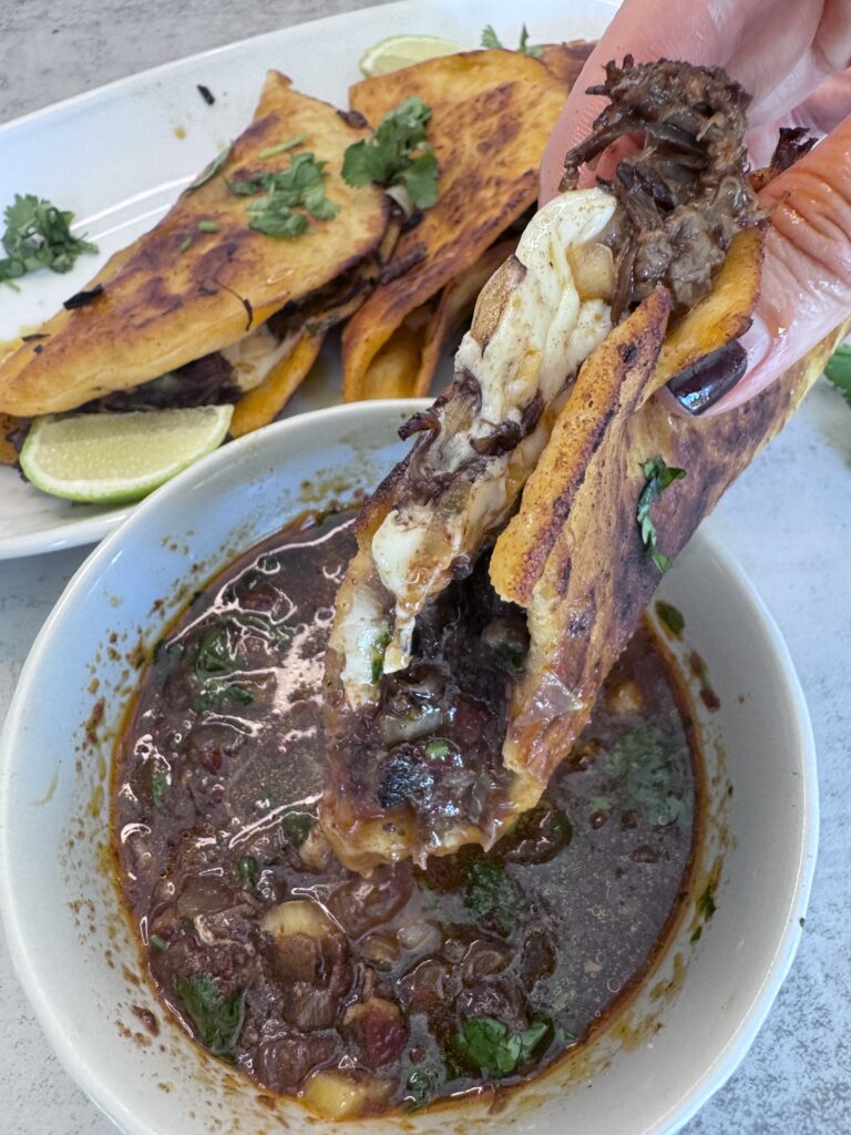 Dip birria tacos in broth