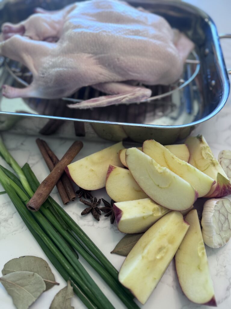 1. Preheat the oven to 390°F (200°C). Stuff the cavity with scallions, garlic, apples, star anise, cinnamon, and bay leaves. Seal the opening with skewers or toothpicks.